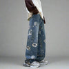 A person wearing Vexlly Baggy Flower Jeans Men Fashion Oversized Wide Leg Jeans stands in a corner with textured stone walls. They sport gray sneakers while maintaining a casual pose, likely selected from an Asian size chart.