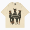 The Trifecta Oversized Doberman Dog Graphic Tee by Vexlly features a captivating graphic of three Dobermans with spiked collars on a beige background. "Dobermanpinscher" and "Blackwork" are stylishly printed in a Gothic font below the image, making it an eye-catching addition to any streetwear collection.