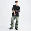 A person with medium-length hair stands posing against a plain white background, embodying Y2K streetwear vibes. They are wearing sunglasses, a Vexlly Bloody Skeleton Graphic Tee, baggy faded jeans with knee patches, and black shoes.