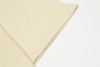 Close-up view of the beige fabric from the Trifecta Oversized Doberman Dog Graphic Tee by Vexlly, highlighting the texture and stitching on the edge. The fabric is neatly folded at the corner on a white background.