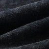 Close-up of a folded piece of dark denim fabric from the ELKMU Official Store's "T-shirt patchwork pour homme, streetwear, hip hop, punk, à la mode, Y2K, noir, 2024" collection. The image captures its rich texture and intricate weave. The material appears thick and durable with visible stitches and a slight sheen under light. This detailed description highlights key elements for identifying relevant SEO keywords related to this contemporary men's fashion item.