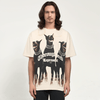 A person with long hair is seen wearing the Vexlly Trifecta Oversized Doberman Dog Graphic Tee. The shirt is beige and showcases three black Dobermans alongside bold text reading "Thoroughbred Represent." Embracing streetwear fashion, they stand against a minimalistic plain white background.