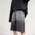 A person is wearing a black long-sleeve shirt paired with Summer Gradient Denim Shorts by Vexlly. These retro-style shorts feature a gray hue with frayed hems, capturing the details of the fabric and design. The backdrop is plain and light, highlighting the shorts' standout features.